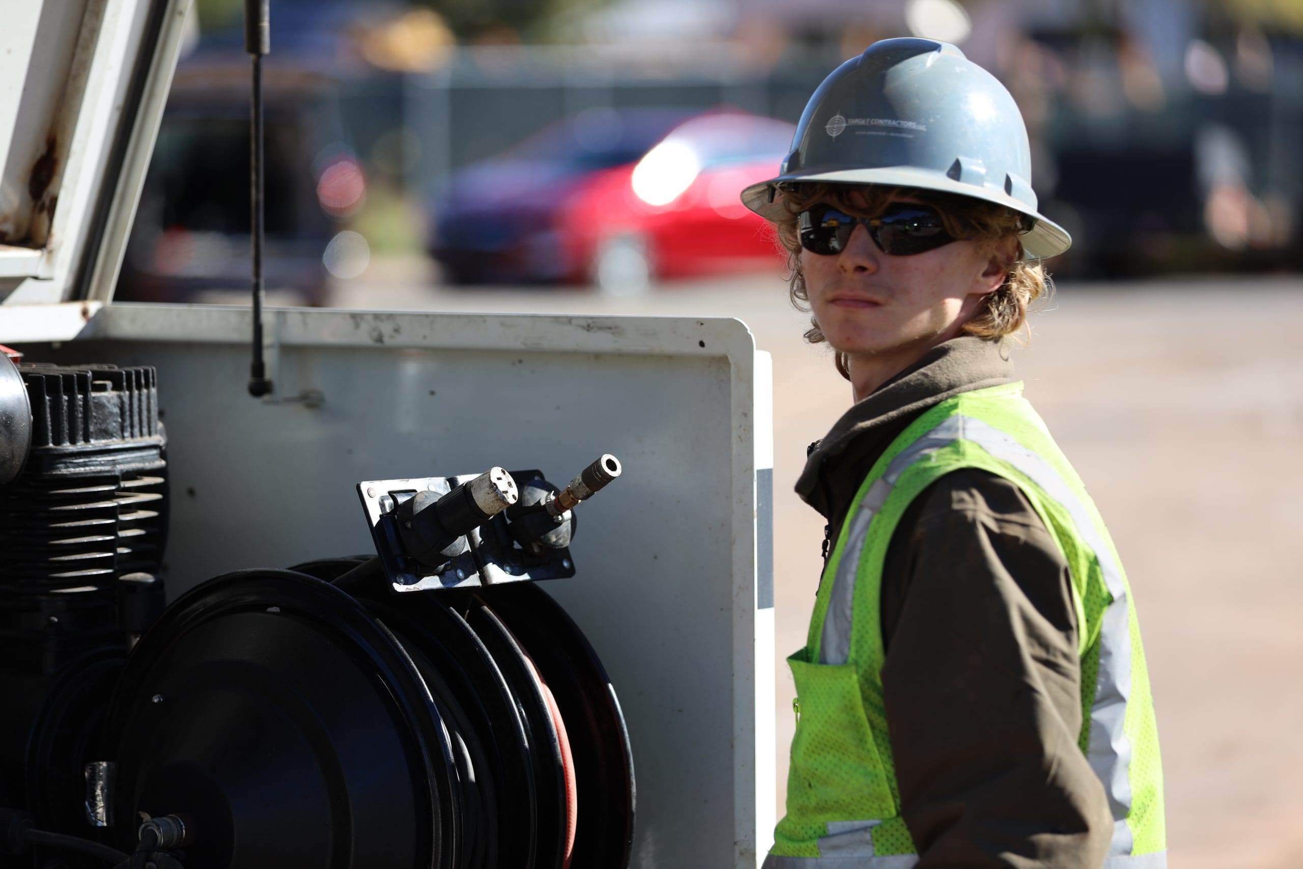 Crew member in hard hat and high-visibility vest beside equipment on a job site