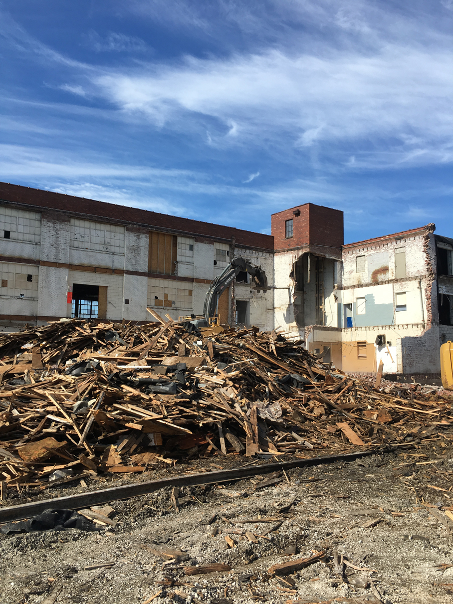 Pile of wood debris in front of a partially demolished building