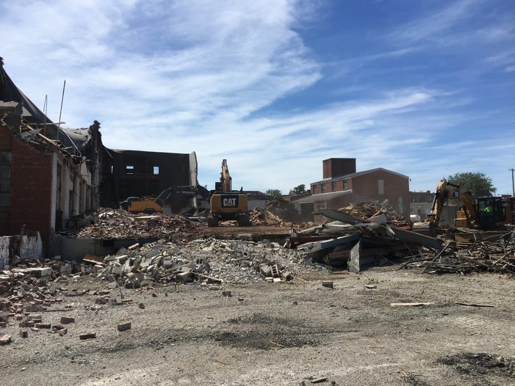 Demolition site with buildings and equipment in the background