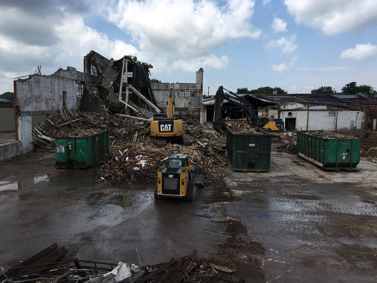 Roll-off containers, debris piles, and equipment sorting material at a demolition site