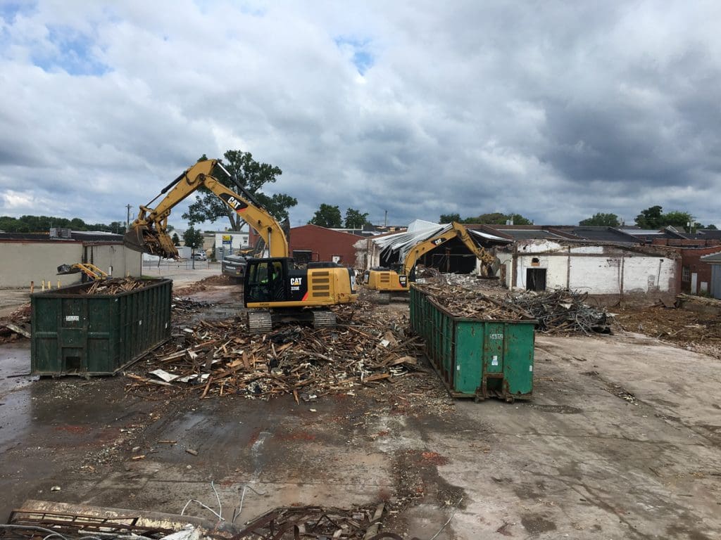 Excavators and dumpsters on a cleared commercial site