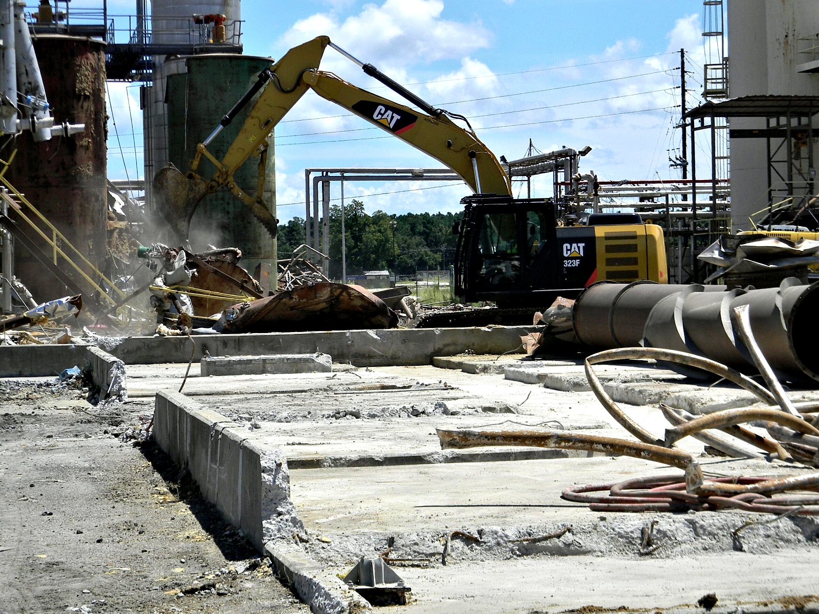 Excavator dismantling steel tanks and structures