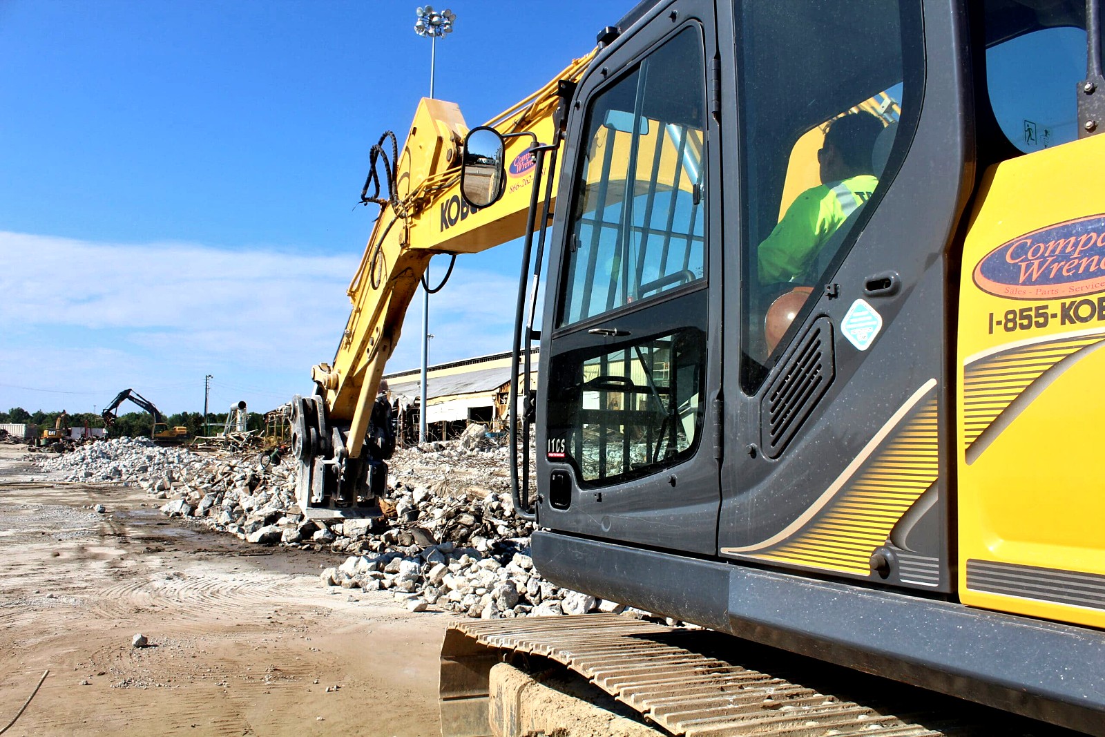 Excavator working on concrete and debris at a demolition site