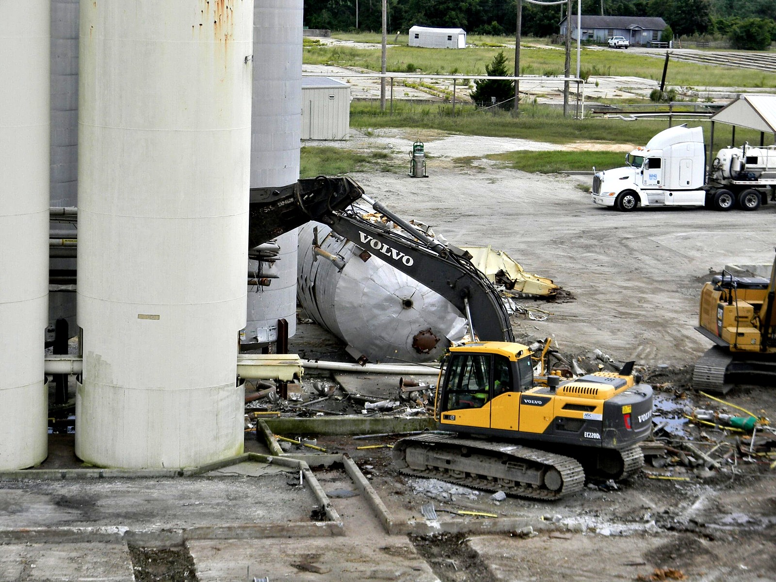 Excavator beside a fallen tank at a terminal