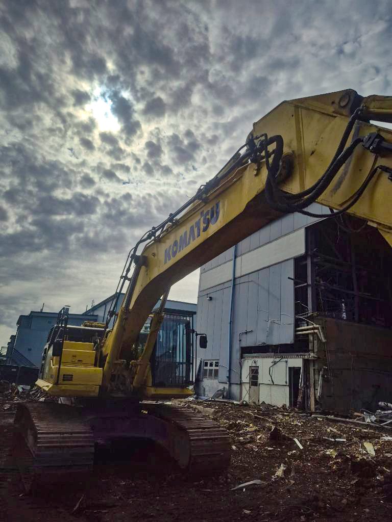 Excavator working beside a hangar-style industrial building