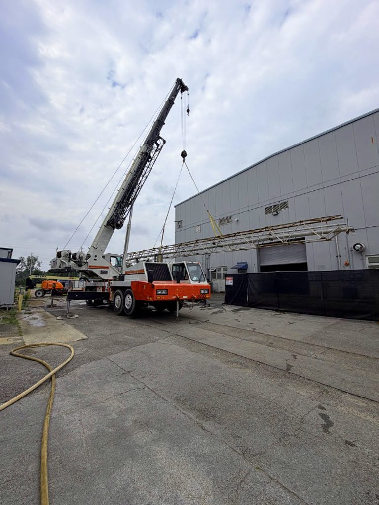 Crane lifting equipment beside a hangar building