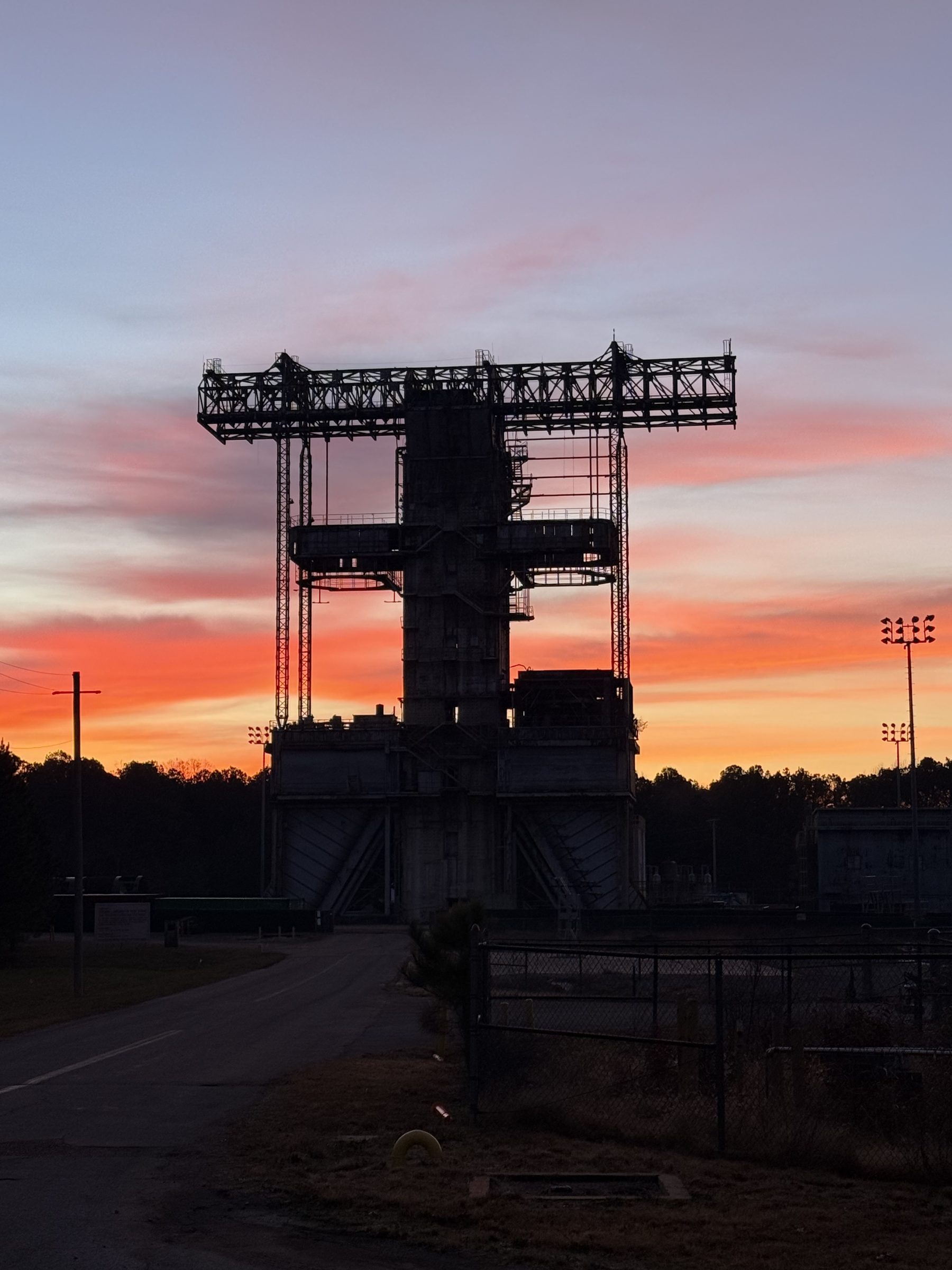 Steel test stand silhouetted against a sunset sky